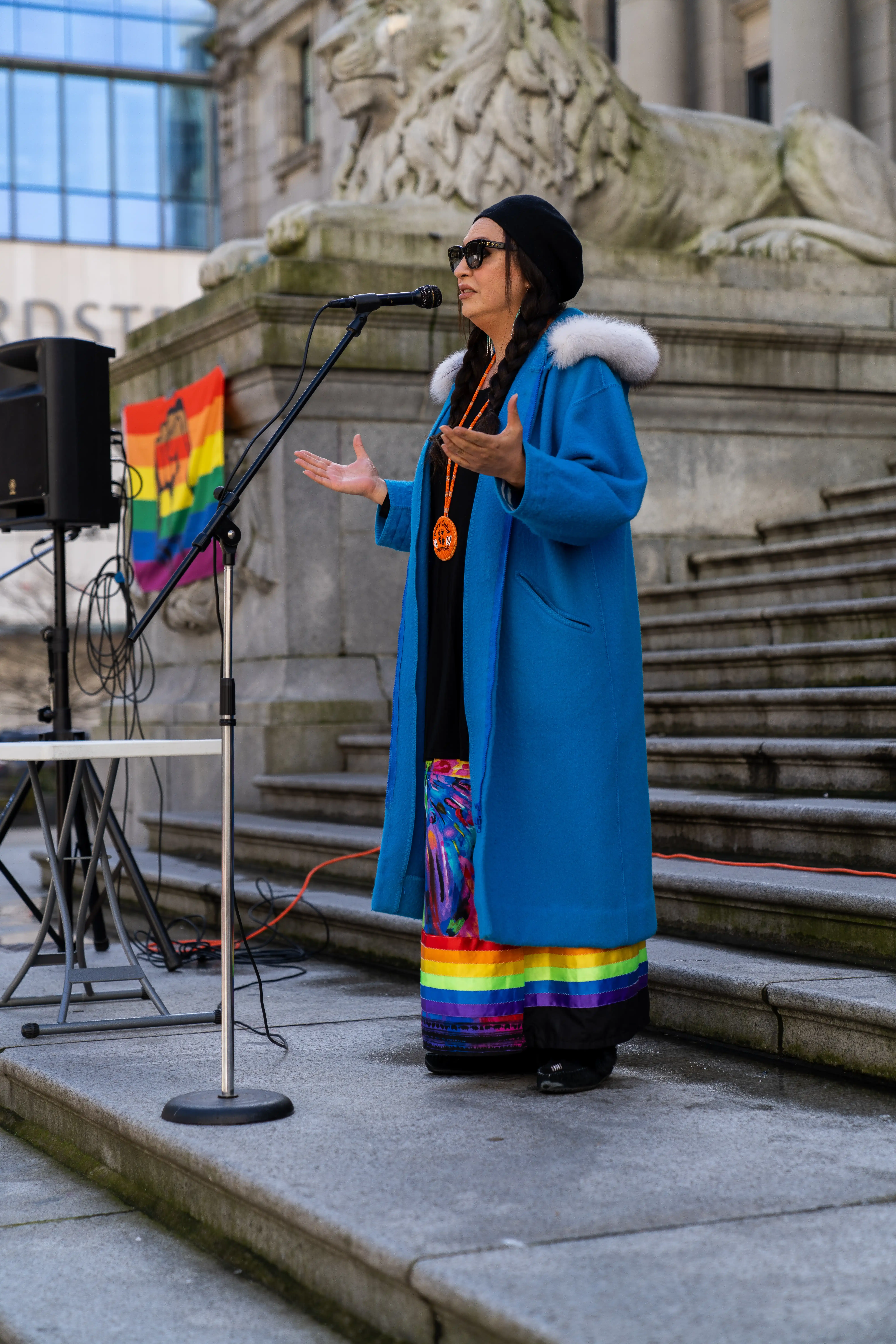 This is an image of Jaylene Tyme, speaking to the crowd. She is speaking into a microphone on large stone stairs outside. 